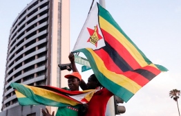 (FILES) In this file photo taken on November 21, 2017, people holding Zimbabwean flags celebrate in the streets of Harare after the resignation of Zimbabwe's president Robert Mugabe.
Zimbabwe has applied to rejoin the Commonwealth, the group said May 21, 2018, marking a major step in the country's international re-engagement after Robert Mugabe was ousted last year. / AFP PHOTO / Marco Longari