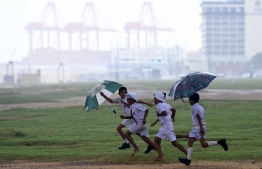 Sri Lankan school children run through a heavy downpour in Colombo on May 18, 2018. / AFP PHOTO / ISHARA S.  KODIKARA