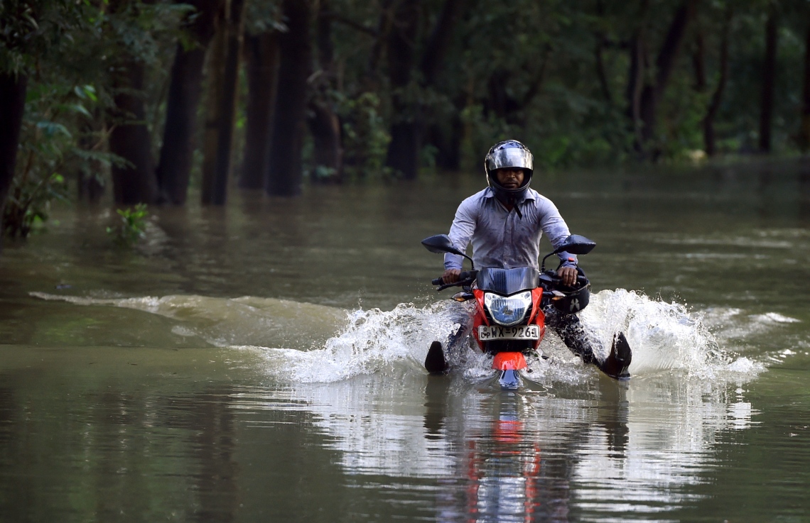 ވެރިރަށް ކޮލަމްބޯގެ ބޭރުން އޮންނަ ބިޔަގަމާގައި ފެންބޮޑުވެފައިވާ މަގަކުން ސައިކަލެއްގައި މީހަކު އިއްޔެ ދަނީ. --ފޮޓޯ:އޭއެފްޕީ