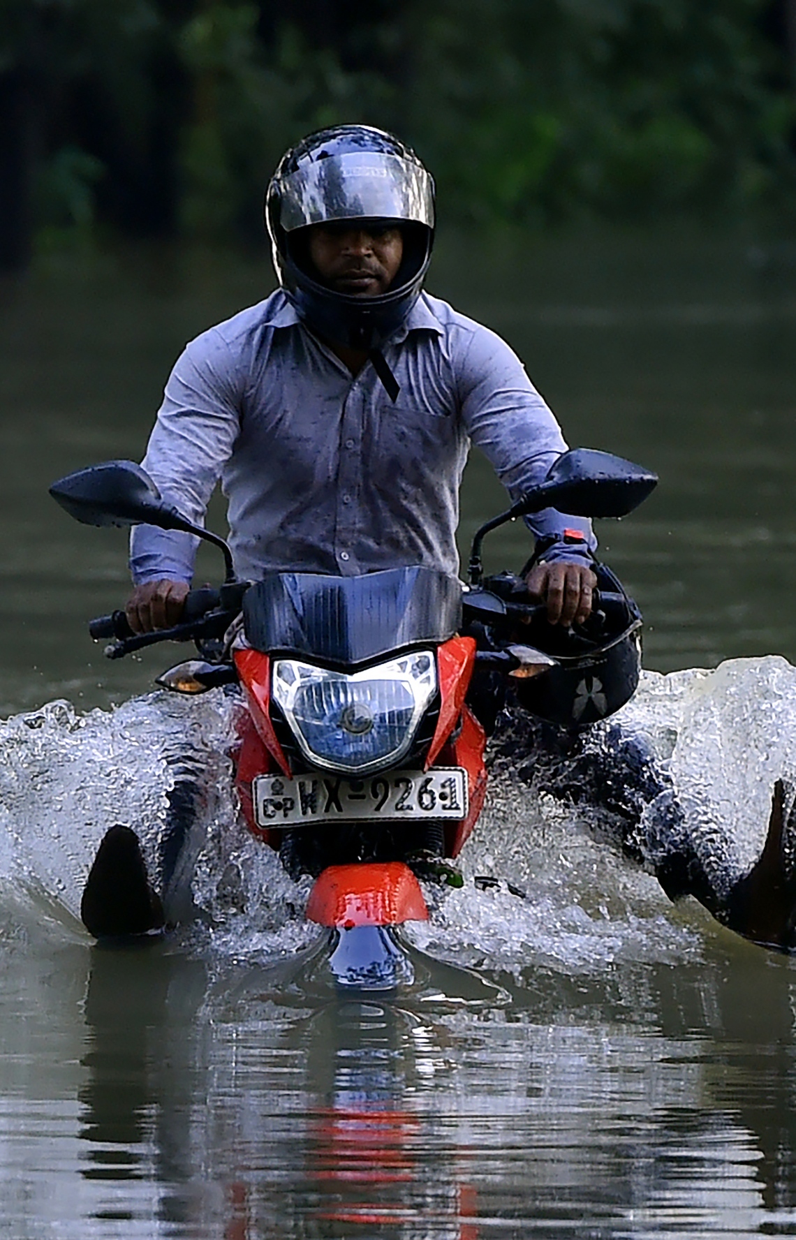 ވެރިރަށް ކޮލަމްބޯގެ ބޭރުން އޮންނަ ބިޔަގަމާގައި ފެންބޮޑުވެފައިވާ މަގަކުން ސައިކަލެއްގައި މީހަކު ދަނީ. --ފޮޓޯ:އޭއެފްޕީ