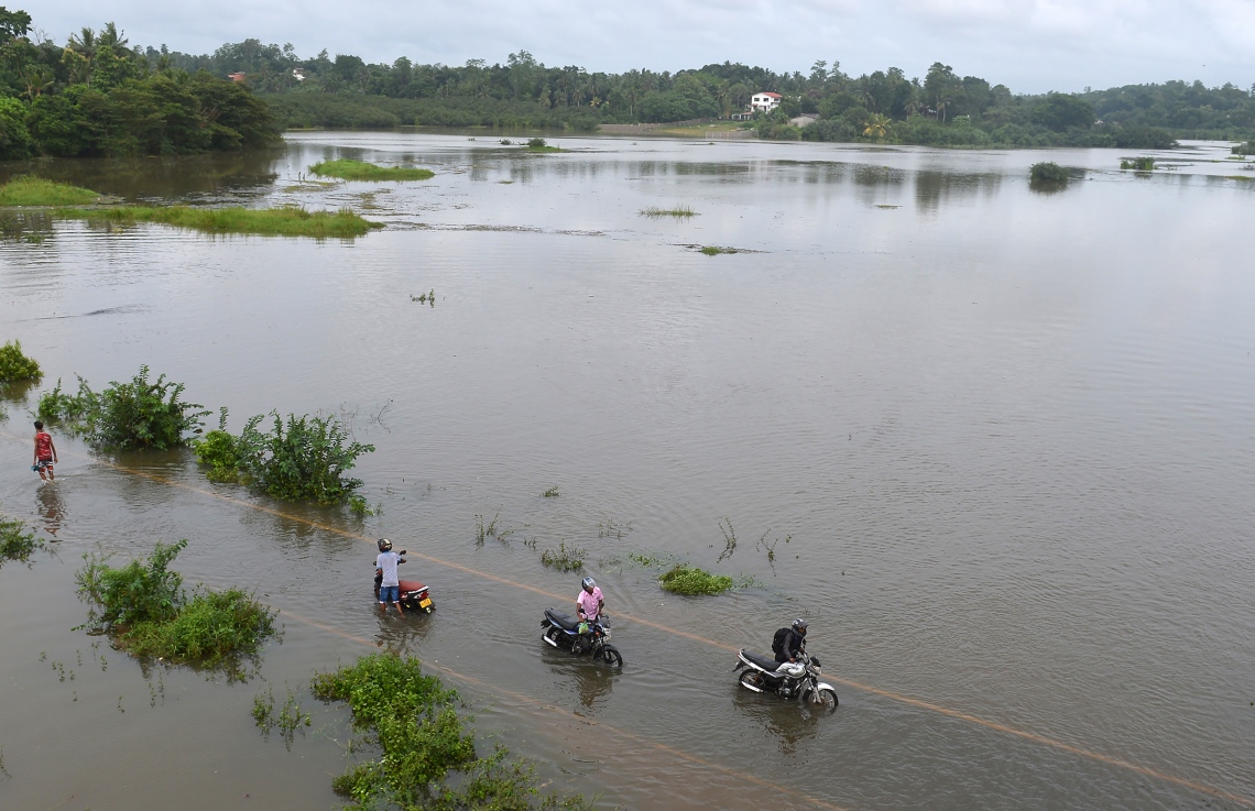 ވެރިރަށް ކޮލަމްބޯގެ ކަޑުވެލައިގައި ފެންބޮޑުވެފައިވާ ސަރަހައްދަކުން ބަޔަކު މޮޓޯސައިކަލް ކޮއްޕައިފައި ގެންދަނީ. --ފޮޓޯ:އޭއެފްޕީ
