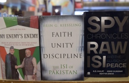 In this picture taken on May 30, 2018, a copy of the book "The Spy Chronicles: RAW, ISI and the Illusion of Peace" (R), co-authored by retired Pakistani lieutenant general Asad Durrani, is seen on display with other similarly-themed books at a bookshop in Islamabad.
It began with hushed conversations in hotels dotted around Asia, and resulted in a nearly unthinkable book: 'Spy Chronicles', a secret collaboration by India and Pakistan's former intelligence heads that has caused uproar in Islamabad. / AFP PHOTO / AAMIR QURESHI / 