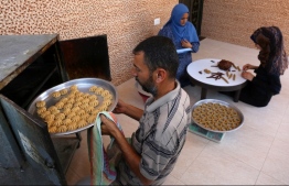 A Palestinian family makes traditional date-filled cookies in preparation for the Eid al-Fitr holiday at their home in Khan Yunis, in the southern Gaza Strip, on June 12, 2018.
Muslims around the world are preparing to celebrate the Eid al-Fitr holiday, which marks the end of the fasting month of Ramadan. / AFP PHOTO / SAID KHATIB
