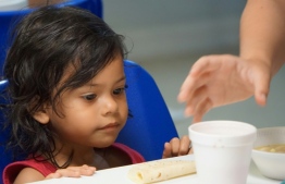 A young girl looks at a cup of soup handed to her by volunteers in a migration center in the border town of McAllen, Texas - Image: AFP