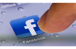 A person clicks the Facebook app icon on their mobile phone. FILE PHOTO: AFP