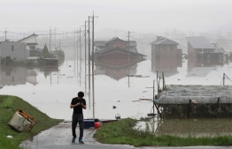 A man stands next to a flooded residential area in Kurashiki, Okayama prefecture on July 8, 2018.
Japan's Prime Minister Shinzo Abe warned on July 8 of a "race against time" to rescue flood victims as authorities issued new alerts over record rains that have killed at least 48 people. / AFP PHOTO / JIJI PRESS / STR / 