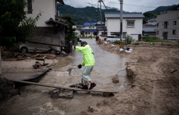 A man gets home over a flooded river in Saka, Hiroshima prefecture on July 8, 2018.
Japan's Prime Minister Shinzo Abe warned on July 8 of a "race against time" to rescue flood victims as authorities issued new alerts over record rains that have killed at least 48 people. / AFP PHOTO / Martin BUREAU