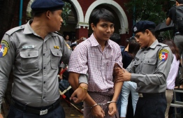 Detained Myanmar journalist Kyaw Soe Oo (C) is escorted by police to a court for his ongoing pre-trial hearing in Yangon on July 9, 2018.
Two Reuters reporters accused of breaking Myanmar's draconian secrecy law during their reporting of the Rohingya crisis must face trial, a judge ruled on July 9, on a charge that carries up to 14 years in jail. / AFP PHOTO / STR