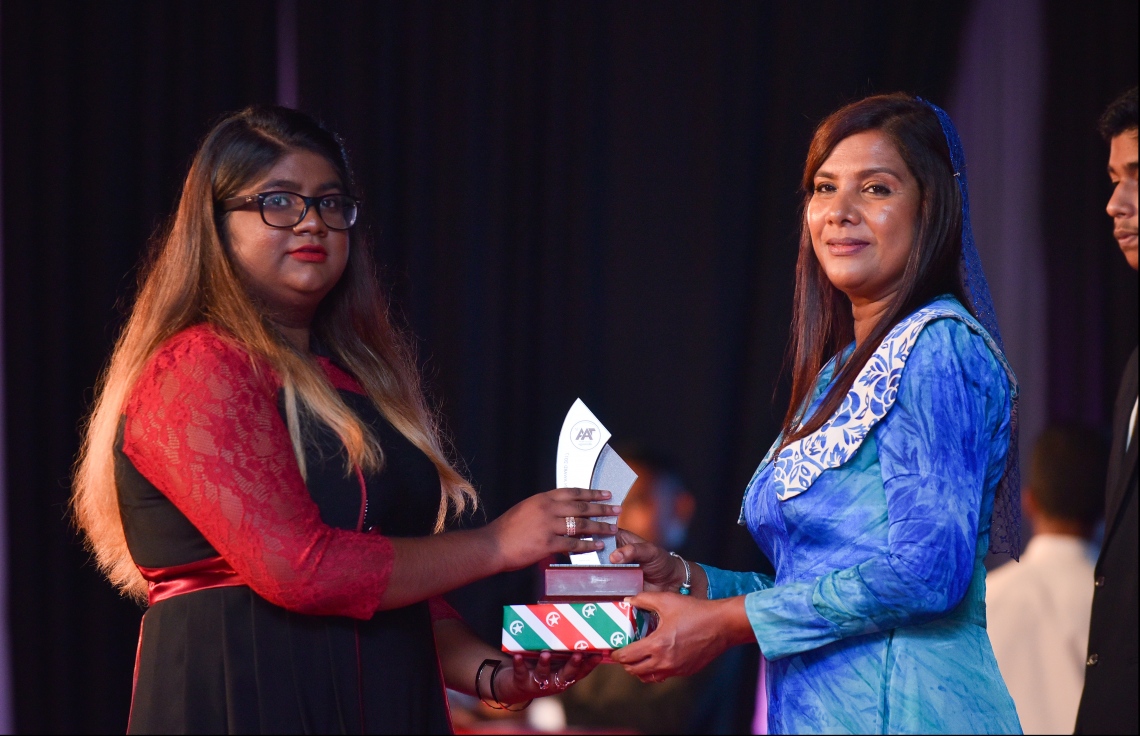 މާލެ: ޖުލައި 9، 2018- މިދިޔަ އަހަރުގެ އޮކްޓޯބަރު/ނޮވެމްބަރުގައި ބޭއްވި އޭ ލެވެލް އިމްތިހާނުގެ ރަންވަނަތައް ހޯދި ދަރިވަރުންނަށް އިނާމު ދިނުމަށް ދަރުބާރުގޭގައި ބޭއްވި ރަސްމިއްޔާތުގައި، އެޑިއުކޭޝަން މިނިސްޓަރު އާއިޝަތު ޝިހާމް، ދަރިވަރަކަށް އެވޯޑާއި އިނާމު ދެއްވަނީ.---ފޮޓޯ: ހުސެއިން ވަހީދު/މިހާރު