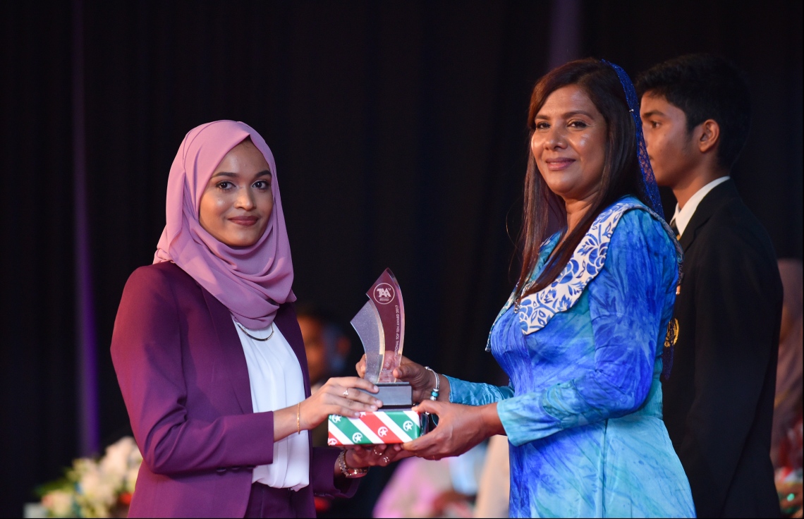 މާލެ: ޖުލައި 9، 2018- މިދިޔަ އަހަރުގެ އޮކްޓޯބަރު/ނޮވެމްބަރުގައި ބޭއްވި އޭ ލެވެލް އިމްތިހާނުގެ ރަންވަނަތައް ހޯދި ދަރިވަރުންނަށް އިނާމު ދިނުމަށް ދަރުބާރުގޭގައި ބޭއްވި ރަސްމިއްޔާތުގައި، އެޑިއުކޭޝަން މިނިސްޓަރު އާއިޝަތު ޝިހާމް، ދަރިވަރަކަށް އެވޯޑާއި އިނާމު ދެއްވަނީ.---ފޮޓޯ: ހުސެއިން ވަހީދު/މިހާރު