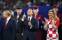 French President Emmanuel Macron (C) gestures between Croatian President Kolinda Grabar-Kitarovic (R) and Russian President Vladimir Putin during the trophy ceremony at the end of the Russia 2018 World Cup final football match between France and Croatia at the Luzhniki Stadium in Moscow on July 15, 2018. / AFP PHOTO / FRANCK FIFE / 