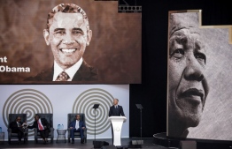 Former US President Barack Obama (R) speaks next to the Chancellor of the University of Johannesburg, Professor Njabulo Ndebele (L), South African President Cyril Ramaphosa (2ndL) and Patrice Motsepe, businessman and founder of the Motsepe Foundation, during the 2018 Nelson Mandela Annual Lecture at the Wanderers cricket stadium in Johannesburg on July 17, 2018.
Former US president Barack Obama will deliver the Nelson Mandela Annual Lecture, urging young people to fight to defend democracy, human rights and peace, to a crowd of 15,000 people at the club as the centrepiece of celebrations marking 100 years since Nelson Mandela's birth. Obama has made relatively few public appearances since leaving the White House in 2017, but he has often credited Mandela for being one of the great inspirations in his life.
 / AFP PHOTO / MARCO LONGARI
