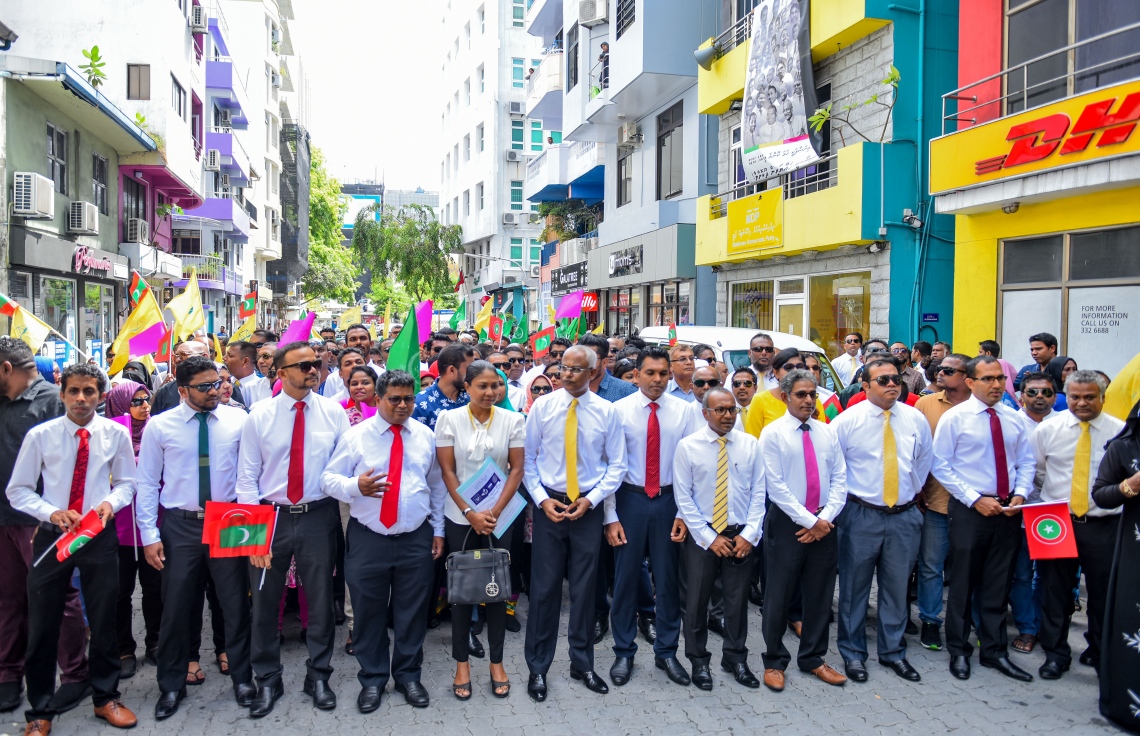 މާލެ: ޖުލައި 26، 2018- މި އަހަރުގެ ރިޔާސީ އިންތިޚާބަށް ކުރިމަތިލެއްވުމަށްޓަކައި އިދިކޮޅު ކެންޑިޑޭޓް އިބްރާހިމް މުހައްމަދު ސޯލިހް (އިބޫ) އާއި އޭނާގެ ރަނިންމޭޓް ފައިސަލް ނަސީމްގެ ފޯމު ހުށަހެޅުއްވުމަށްޓަކައި، އެމްޑީޕީގެ އޮފީހުން ފެށިގެން އިލެކްޝަންސް ކޮމިޝަނާ ހަމައަށް އިދިކޮޅު ކޯލިޝަންގެ ސަޕޯޓަރުންނާ އެކު ހިންގަވާފައި ވަޑައިގަންނަވަނީ.---ފޮޓޯ: އަހުމަދު ނިޝާތު/މިހާރު