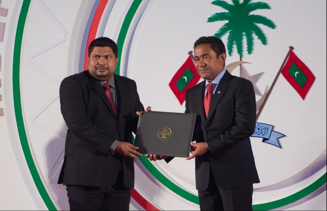 މާލެ: ޖުލައި 26، 2018- ރާއްޖޭގެ މިނިވަން ކަމަށް 53 އަހަރު ފުރުން ފާހަގަ ކުރުމަށް ޖުމްހޫރީ މައިދާނުގައި ބޭއްވި ރަސްމިއްޔާތުގައި، ވިޒުއަލް އާޓްސްގެ ދާޢިރާއިން އަލީ ޝިފާއު (މޮގާ) އަށް ރައީސް ޔާމީން، ހިތްވަރުދިނުމުގެ ގައުމީ އިނާމު ދެއްވަނީ.---ފޮޓޯ: ހުސައިން ވަހީދު/މިހާރު