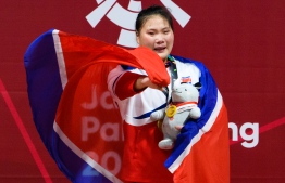 Gold medallist North Korea's Kim Hyo Sim reacts during the awards ceremony for the women's 63kg Group A weightlifting event at the 2018 Asian Games in Jakarta on August 24, 2018. / AFP PHOTO / ANTHONY WALLACE
