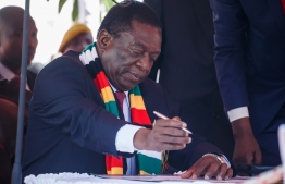 Zimbabwe President Emmerson Mnangagwa signs documents after taking his oath of office in Harare on August 26, 2018.
Emmerson Mnangagwa was officially sworn in as president of Zimbabwe after winning a bitterly contested election that marked the country's first vote since Robert Mugabe was ousted from power.   / AFP PHOTO / Jekesai NJIKIZANA