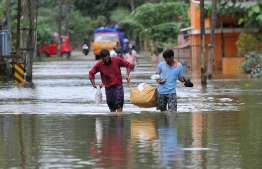 Indian men carry food and water aid distributed to those stranded by floods in Pandanad in Alappuzha District in the south Indian state of Kerala on August 21, 2018.
More than one million people have swarmed relief camps in India's Kerala state to escape devastating monsoon floods that have killed more than 410 people, officials said Tuesday as a huge international aid operation gathered pace. / AFP PHOTO / MANJUNATH KIRAN