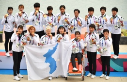 Unified Korea's gold medallists pose for photographers during the awards ceremony for the women's canoe traditional 500m boat race at the 2018 Asian Games in Palembang on August 26, 2018. / AFP PHOTO / ADEK BERRY