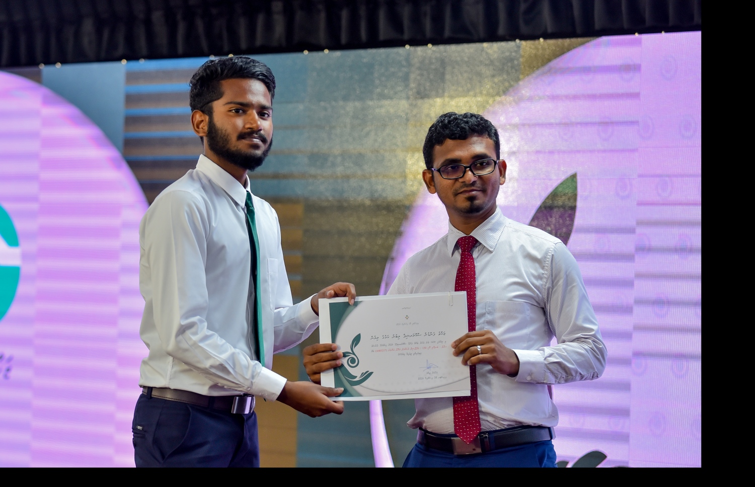 ޒަކާތު ފަންޑުގެ ސްކޮލަޝިޕްގެ ލިޔުން ހަވާލުކުރުމުގެ ރަސްމިއްޔާތުގައި ސްކޮލަޝިޕް ލިބުނު ދަރިވަރަކަށް، ފިނޭންސް މިނިސްޓަރު އަހުމަދު މުނައްވަރު (ކ) ލިޔުން ހަވާލުކޮށްދެއްވަނީ.-- ފޮޓޯ: އަހުމަދު ނިޝާތު /މިހާރު