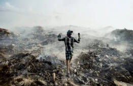 A Bangladeshi immigrant helps keep a fire going in the country's largest trash dump at Thilafushi Island. PHOTO: MOHAMED MUHA