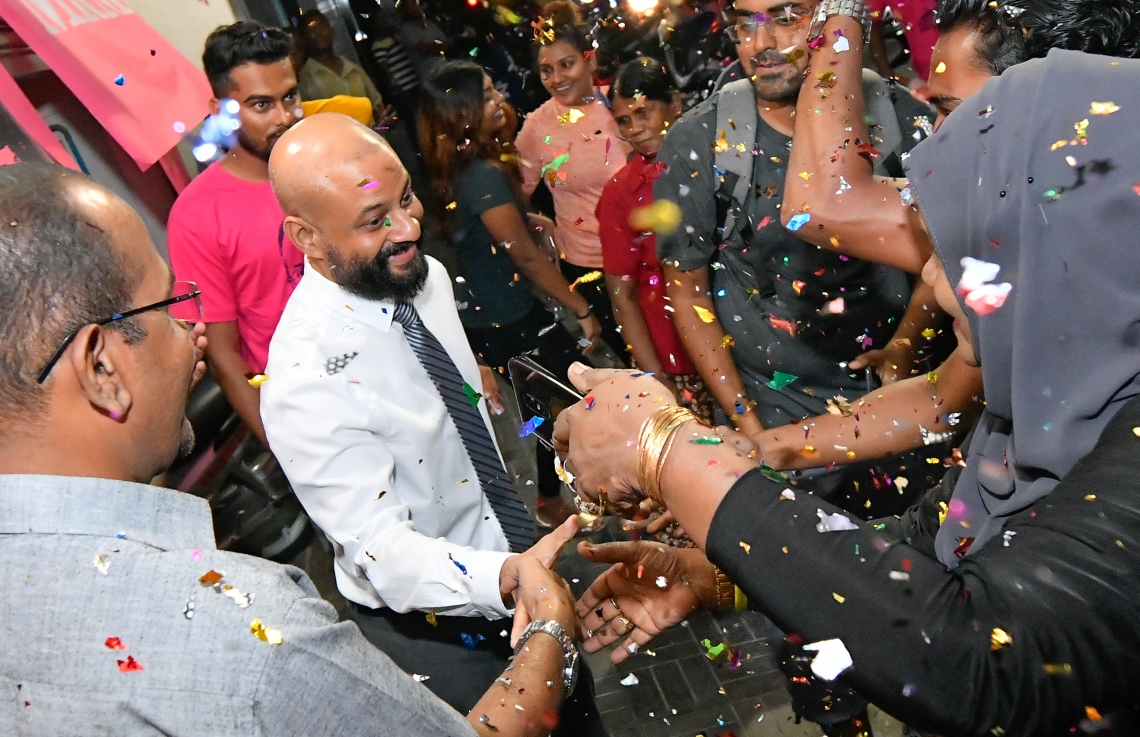 މާލެ: ސެޕްޓެމްބަރު 30، 2018- ޝަހްސު އޮޅުވާލުމުގެ ދައުވާއެއް ސާބިތުވެ، ހަތަރު މަހާއި 24 ދުވަހުގެ ޖަލު ހުކުމެއް ތަންފީޒު ކުރަމުންދިޔަ ދިއްގަރު ދާއިރާގެ މެމްބަރު އަދި މައުމޫންގެ ދަރިކަލުން އަހުމަދު ފާރިސް މައުމޫން ކަފާލާތުގެ ދަށުން ބަންދުން މިނިވަންވެ ވަޑައިގަތުމަށްފަހު، އެންދެރިމާގެއަށް ވަޑައިގަތުމުން މަރުހަބާ ދެންނެވުމުގެ ގޮތުން އެސަރަހައްދަށް އެއްވެ ތިބި މީހުންނާ ސަލާމް ކުރައްވަނީ.---ފޮޓޯ: ހުސައިން ވަހީދު/މިހާރު