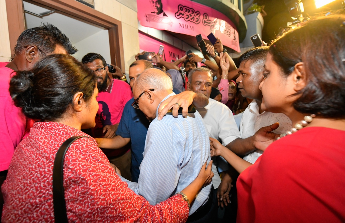 މާލެ: ސެޕްޓެމްބަރު 30، 2018- ގާނޫނާ ޚިލާފަށް ވެރިކަން ވައްޓާލަން އުޅުނު ކަމުގެ ތުހުމަތުގައި ހައްޔަރުކުރުމަށްފަހު މާފުށީ ޖަލުގައި ހުކުމް ތަންފީޒު ކުރައްވަމުން ގެންދެވި ކުރީގެ ރައީސް މައުމޫން އަބްދުލްގައްޔޫމް ކަފާލާތުގެ ދަށުން މިނިވަންވެ ވަޑައިގަތުމަށްފަހު އެންދެރިމާގެއަށް ވަޑައިގަންނަވާއިރު އަރިހުގައި ދެ ދަރިކަނބަލުން ކަމަށްވާ ޔުމްނާ އަދި ދުންޔާ މައުމޫން---ފޮޓޯ: ހުސައިން ވަހީދު/މިހާރު