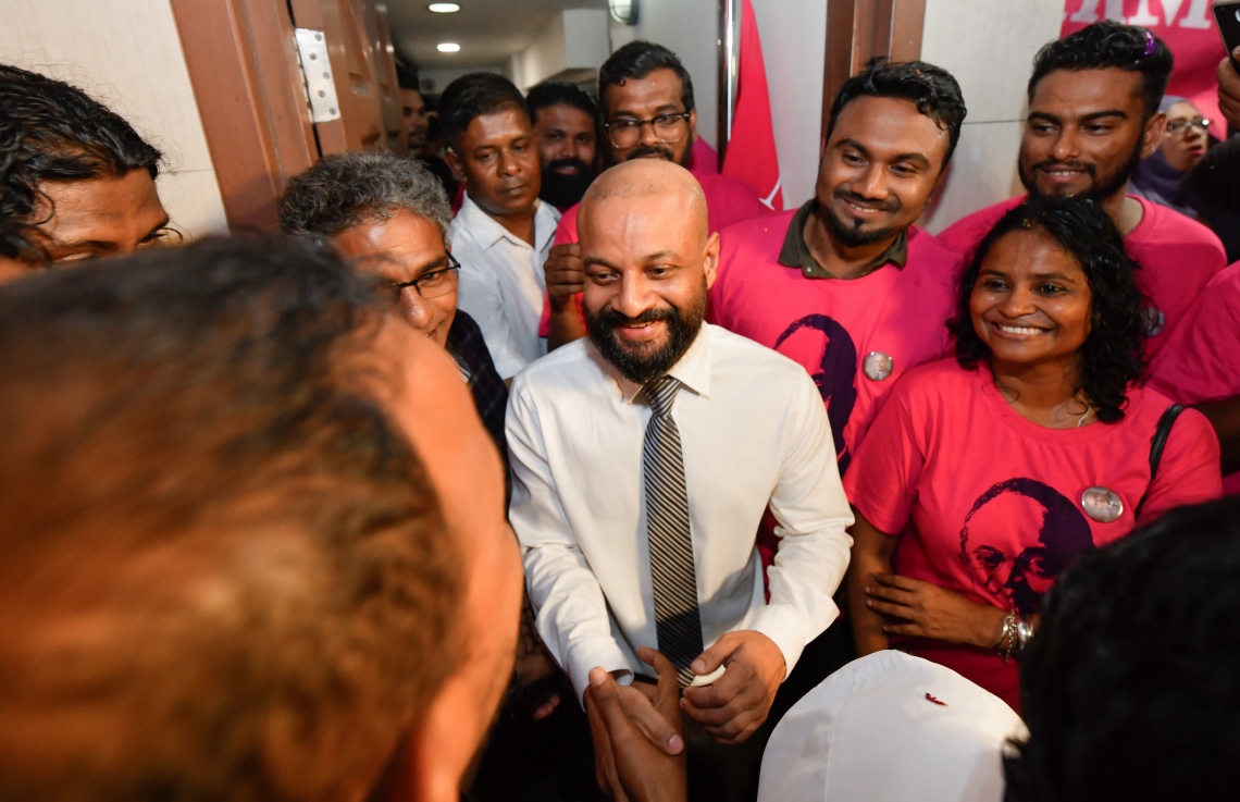 މާލެ: ސެޕްޓެމްބަރު 30، 2018- ޝަހްސު އޮޅުވާލުމުގެ ދައުވާއެއް ސާބިތުވެ، ހަތަރު މަހާއި 24 ދުވަހުގެ ޖަލު ހުކުމެއް ތަންފީޒު ކުރަމުންދިޔަ ދިއްގަރު ދާއިރާގެ މެމްބަރު އަދި މައުމޫންގެ ދަރިކަލުން އަހުމަދު ފާރިސް މައުމޫން ކަފާލާތުގެ ދަށުން ބަންދުން މިނިވަންވެ ވަޑައިގަތުމަށްފަހު، ގެކޮޅަށް ވަޑައިގަތުމުން މަރުހަބާ ދެންނެވުމަށް އެ ސަރަހައްދަށް އެއްވެ ތިބި މީހުންނާ ސަލާމް ކުރައްވަނީ.---ފޮޓޯ: ހުސައިން ވަހީދު/މިހާރު