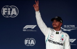 Mercedes' British driver Lewis Hamilton flashes a victory sign after taking the pole position of the qualifying session for the Formula One Japanese Grand Prix at Suzuka on October 6, 2018. / AFP PHOTO / Behrouz MEHRI