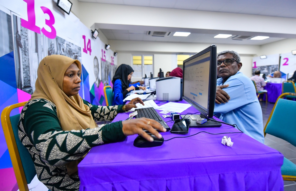 މާލެ: އޮކްޓޯބަރު 10، 2018: ހުޅުމާލޭގެ ދެ ވަނަ ފިޔަވަހިން 400 ގޯތި ގަންނަން ބޭނުންވާ މީހުންނަށް އެ ފުރުސަތު ހުޅުވާލުމާ އެކު، ހައުސިން މިނިސްޓްރީ ކައިރީގައި ދަމާލި ދިގު ކިޔޫގައި ބައިވެރިވެގެން މިއަދު ދޫކުރި 500 ނަމްބަރު ނެގި މީހުންގެ ތެރެއިން މީހެއްގެ ފޯމު މިނިސްޓްރީގެ މުވައްޒަފަކު ބަލައިގަންނަނީ،---ފޮޓޯ: ހުސައިން ވަހީދު/މިހާރު