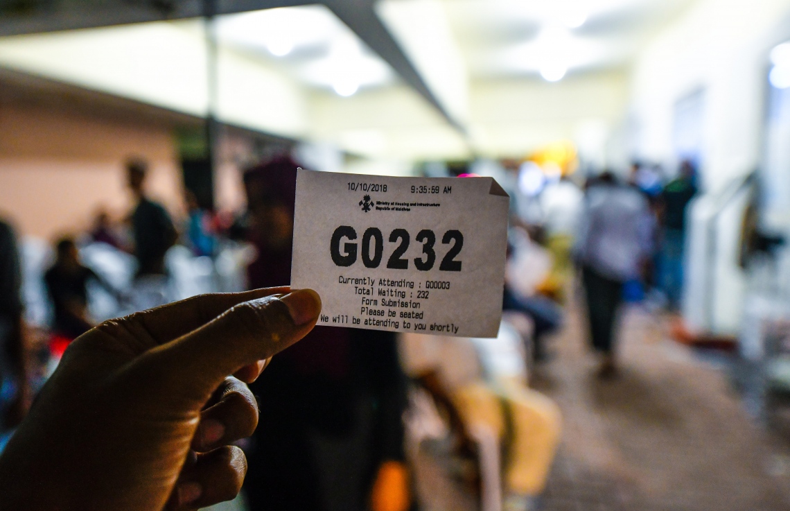 މާލެ: އޮކްޓޯބަރު 10، 2018: މިއަދުގެ ކިޔޫ ނަމްބަރެއް ލިބުނު މީހަކު އޭނާގެ ނަމްބަރު ކެމެރާއަށް ދައްކާލަނީ. ހުޅުމާލޭގެ ދެ ވަނަ ފިޔަވަހިން 400 ގޯތި ގަންނަން ބޭނުންވާ މީހުންނަށް އެ ފުރުސަތު ހުޅުވާލުމާ އެކު، ހައުސިން މިނިސްޓްރީ ކައިރީގައި ދަމާލި ކިޔޫ ދިގުދެމިގެން އައިސް މިއަދު ދޫކުރި 500 ނަމްބަރު ހުސްވުމުން، މާދަމާ ދޫކުރާ 500 ނަމްބަރުގައި ލައްވާލާތޯ މިރޭގެ ނިދި ނަގާލުމަށްފަހު ގިނައަދަދެއްގެ މީހުން ވަނީ މަގުމަތީ ކިޔޫ ޖައްސާފައި،---ފޮޓޯ: ހުސައިން ވަހީދު/މިހާރު