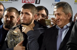 UFC lightweight champion Khabib Nurmagomedov (L) of Russia holds his champions belt next to his father Abdulmanap (C) during a ceremony upon the arrival at the Anzhi-arena stadium in Makhachkala on October 8, 2018. - He defeated Conor McGregor of Ireland in their UFC lightweight championship bout by way of submission during the UFC 229 event inside T-Mobile Arena on October 6, 2018 in Las Vegas, Nevada. (Photo by Vasily MAXIMOV / AFP)