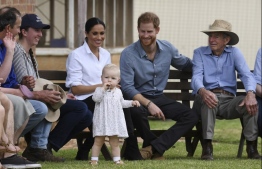 Britain's Prince Harry (2nd R) and his wife Meghan, the Duchess of Sussex (C) watch thirteen-month-old Ruby Carroll during a visit to the drought-affected farm Mountain View in Dubbo in Dubbo on October 17, 2018. - The rain was a welcomed accompaniment when Harry and his expectant wife Meghan visited a drought-stricken region of Australia Wednesday, where the prince commended resilient farmers for persisting through years-long dry spells. (Photo by DEAN LEWINS / various sources / AFP)