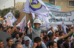 A Syrian girl sits on the shoulders of a man while waving a flag bearing the emblem of the Syrian Civil Defence (also known as "The White Helmets") during a gathering in Anjara in the western countryside of Aleppo province on October 19, 2018 commemorating injured members of the White Helmets and protesting against Russian involvement in Syria. - Russia's UN representative had on October 11 described the White Helmets rescue volunteers as a "threat" and demanded their removal from the war-torn country, during a closed meeting of the UN Security Council called by Moscow, according to a diplomat present at the talks in the New York headquarters. (Photo by Aaref WATAD / AFP)