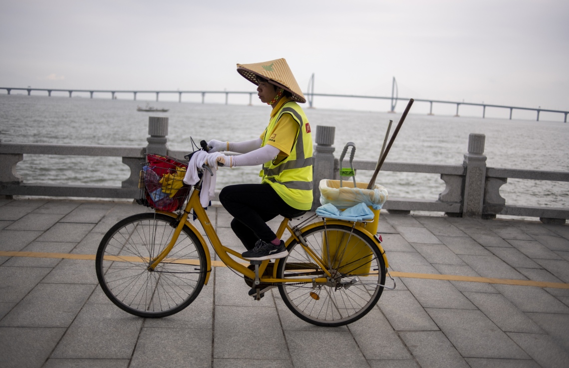 ހޮންކޮން-ޒުހައި-މަކާއޫ ބްރިޖުގެ ކައިރިން ޗައިނާގެ މަސައްކަތު މީހަކު ބައިސްކަލްގައި ދަނީ. --ފޮޓޯ:އޭއެފްޕީ