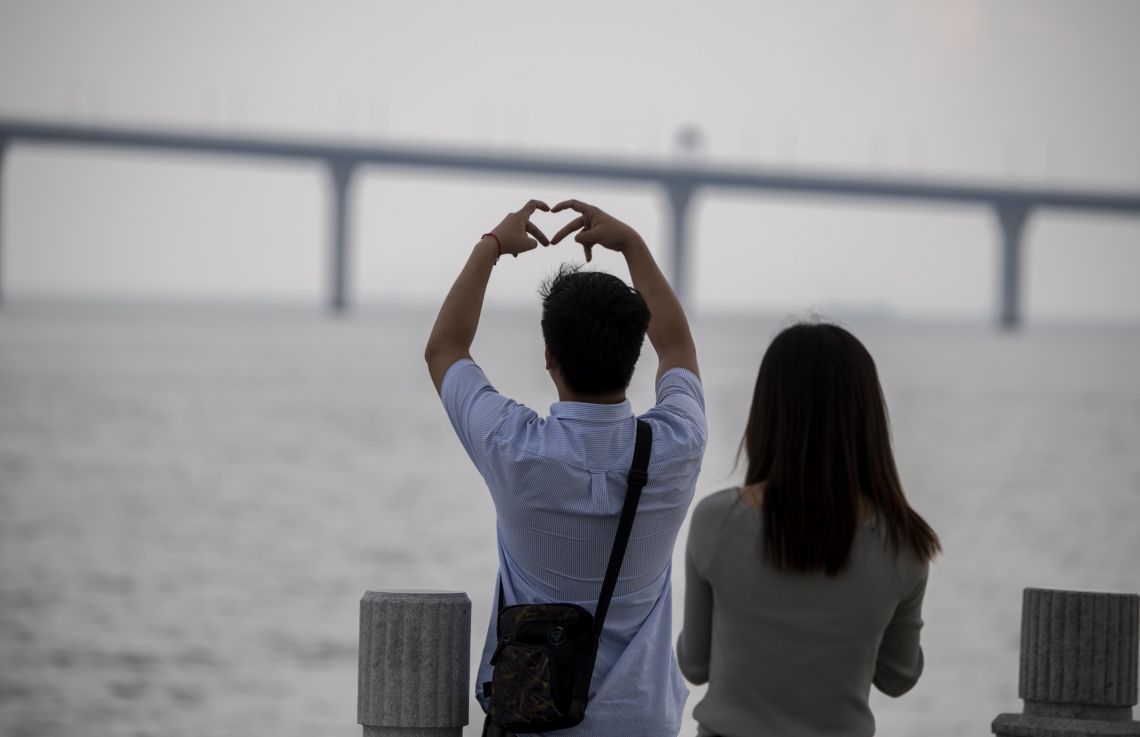 ހޮންކޮން-ޒުހައި-މަކާއޫ ބްރިޖުގެ ފޮޓޯއަކަށް ދެ މީހަކު ތައްޔާރުވެގެން. --ފޮޓޯ:އޭއެފްޕީ