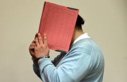 Former nurse Niels H. masks his face with a folder on his arrival in the courtroom at the regional court in Oldenburg, Germany, December 9, 2014. REUTERS/Fabian Bimmer/Files