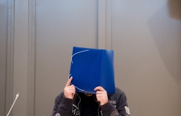 Former nurse Niels Hoegel, accused of killing more than 100 patients in his care, hides behind a folder as he arrives in the courtroom, on October 2018 in Oldenburg, northern Germany, for the start of his trial. - Hoegel, 41, has already spent nearly a decade in prison for other patient deaths, and is accused of intentionally administering medical overdoses to victims so he could bring them back to life at the last moment. (Photo by Julian Stratenschulte / POOL / AFP)