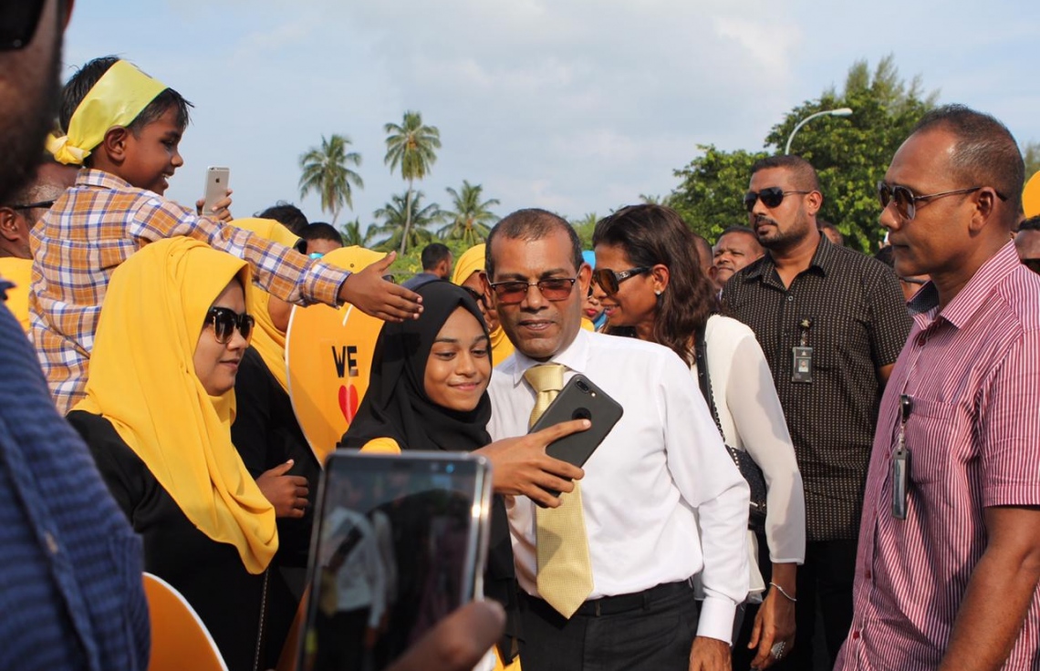 އައްޑޫ :ނޮވެމްބަރު 5، 2018: ކުރީގެ ރައީސް މުހައްމަދު ނަޝީދު އައްޑޫއަށް ކުރެއްވި ދަތުރުފުޅުގައި ނަޝީދަށް މަރުހަބާ ކިއުމަށް އެއްވެ ތިބި މީހުންނާއެކު ފޮޓޯއަކަށް ހުއްޓިވަޑައިގެން.-- ފޮޓޯ: އެމްޑީޕީ