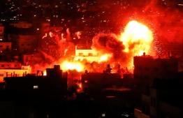 A picture taken on November 12, 2018, shows a ball of fire above the building housing the Hamas-run television station al-Aqsa TV in the Gaza Strip during an Israeli air strike. - Israeli air strikes in Gaza killed three Palestinians and destroyed a Hamas TV building on November 12 after a barrage of rocket fire from the enclave, as renewed violence threatened to derail efforts to end months of unrest. (Photo by MAHMUD HAMS / AFP)