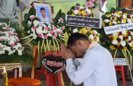 A mourner prays in front of a portrait of 13-year-old Muay Thai boxer Anucha Tasako next to his coffin during a funeral at a Buddhist temple in Samut Prakan province on November 14, 2018. - Thais have reacted with shock and anger after Tasako died during a charity bout, reviving calls for a ban on fights between children in the brutal Muay Thai martial art. (Photo by Romeo GACAD / AFP)