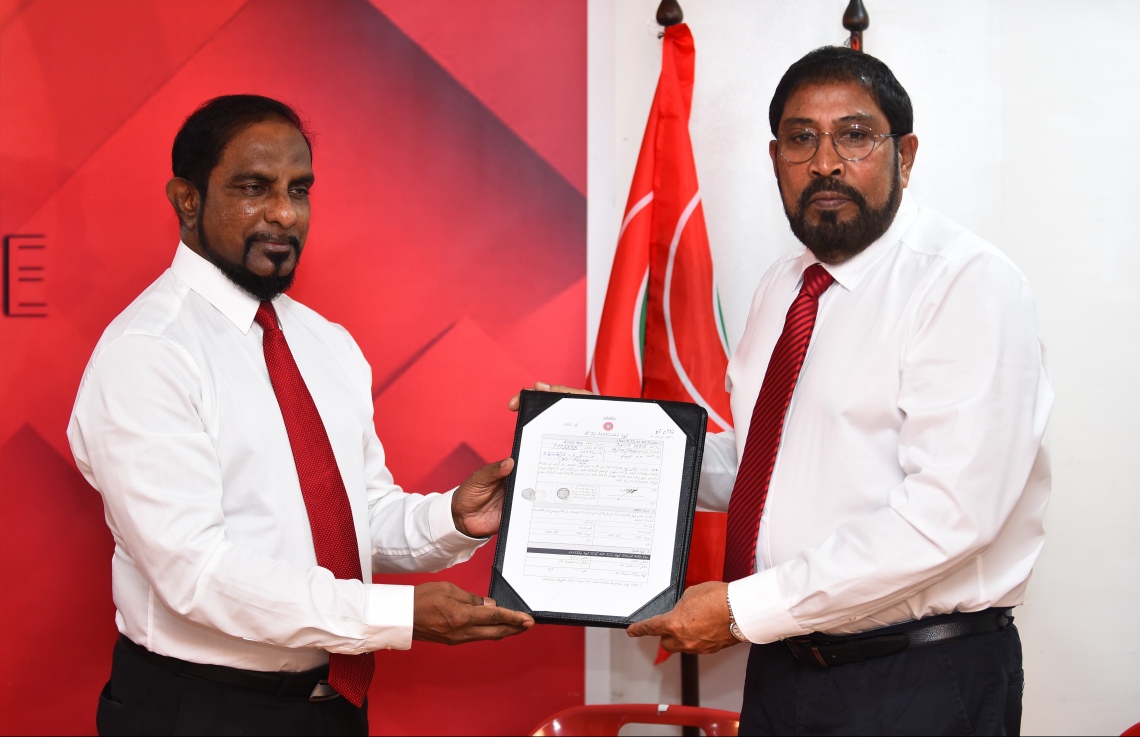 މާލެ: ނޮވެމްބަރު 25، 2018- ކަނޑިތީމު ދާއިރާގެ ޕީޕީއެމްގެ މެމްބަރު މުހައްމަދު ހުސައިން ޖުމްހޫރީ ޕާޓީއަށް ސޮއިކުރެއްވުމަށް ފަހު އޭނާގެ ފޯމު އެ ޕާޓީގެ ލީޑަރު ގާސިމް އިބްރާހީމްއާ ހަވާލު ކުރައްވަނީ.---ފޮޓޯ: ހުސައިން ވަހީދު/މިހާރު