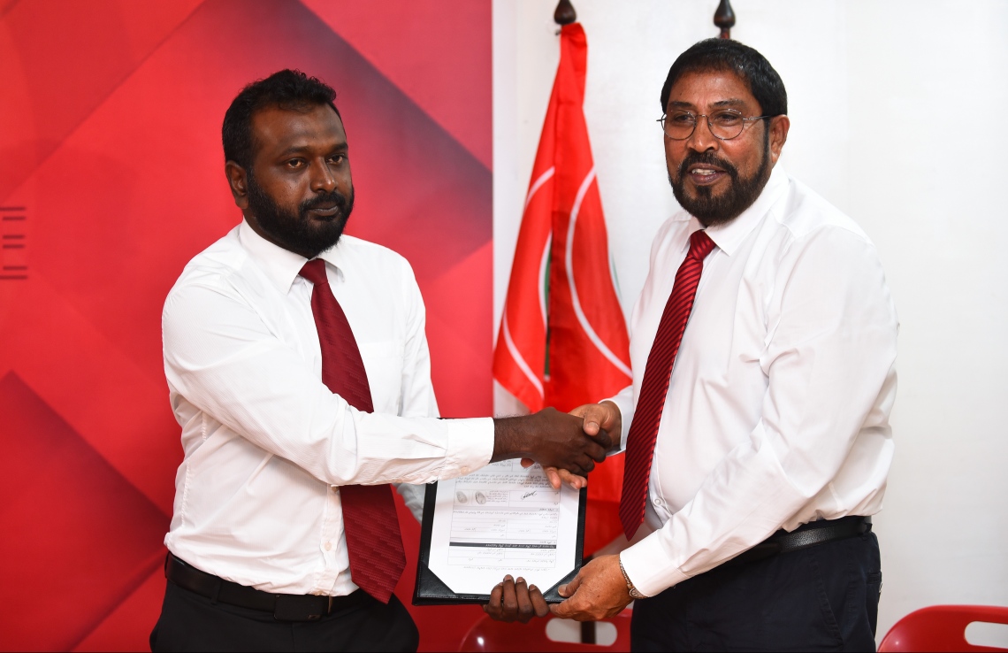 މާލެ: ނޮވެމްބަރު 25، 2018- މާވަށު ދާއިރާގެ ޕީޕީއެމްގެ މެމްބަރު އަޒްހާން ފަހުމީ ޖުމްހޫރީ ޕާޓީއަށް ސޮއިކުރެއްވުމަށް ފަހު އޭނާގެ ފޯމު އެ ޕާޓީގެ ލީޑަރު ގާސިމް އިބްރާހީމްއާ ހަވާލު ކުރައްވަނީ.---ފޮޓޯ: ހުސައިން ވަހީދު/މިހާރު