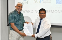 Environment Minister Dr. Hussain Rasheed (R) hands over documents to an environment programme. PHOTO: HUSSAIN WAHEED/MIHAARU