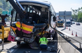A recovery worker looks at the damaged front section of a coach window after it collided with a taxi in Hong Kong on November 30, 2018. PHOTO: AFP