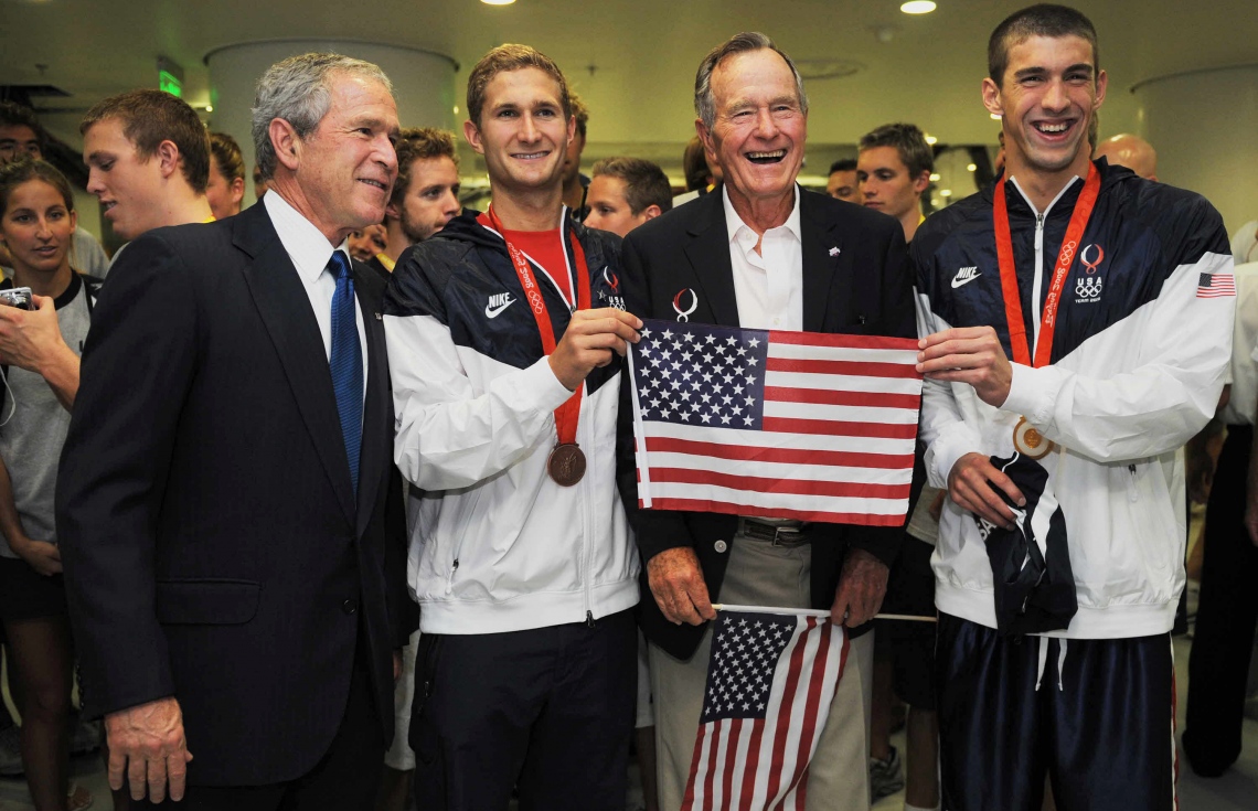 އެމެރިކާގެ ފެތުންތެރިޔާ މައިކަލް ފެލްޕްސް (ކ) އާއި ޖޯޖް ބުޝް އާއި ދަރިކަލުން ޖޯޖް ޑަބްލިއު. ބުޝް (ވ) 2008 ވަނަ އަހަރު ފޮޓޯއަކަށް ހުއްޓިވަޑައިގެން. --ފޮޓޯ:އޭއެފްޕީ