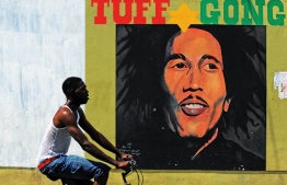 (FILES) In this file photo taken on February 8, 2009 a man pedals past a mural of late musician Bob Marley in Kingston. - Reggae music, whose chill, lilting grooves won international fame thanks to artists like Bob Marley, on November 29, 2018 secured a coveted spot on the United Nations' list of global cultural treasures. (Photo by Jewel SAMAD / AFP)