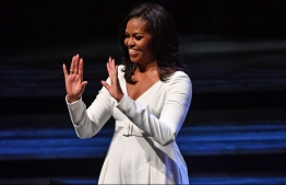 Former US first lady Michelle Obama gestures to the audience on stage at the Royal Festival Hall in London on December 3, 2018, during a tour to promote her memoir, "Becoming". - Former US first lady Michelle Obama's book, "Becoming," sold more than two million copies in North America in its first 15 days. She said Sunday she was canceling book tour visits to Paris and Berlin to attend the funeral of former president George H.W. Bush, who died Friday aged 94. (Photo by Ben STANSALL / AFP)