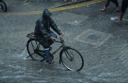 A man riding a bicycle through the heavy showers experienced by Male' City during December 2018. PHOTO: HUSSAIN WAHEED / MIHAARU