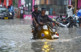Maldives Police Service officers ride their patrol bikes through a flooded street in capital city Male'. FILE PHOTO: AHMED NISHAATH / MIHAARU