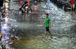 Man crosses a flooded street in Male' on November 5. PHOTO: NISHAN ALI/MIHAARU
